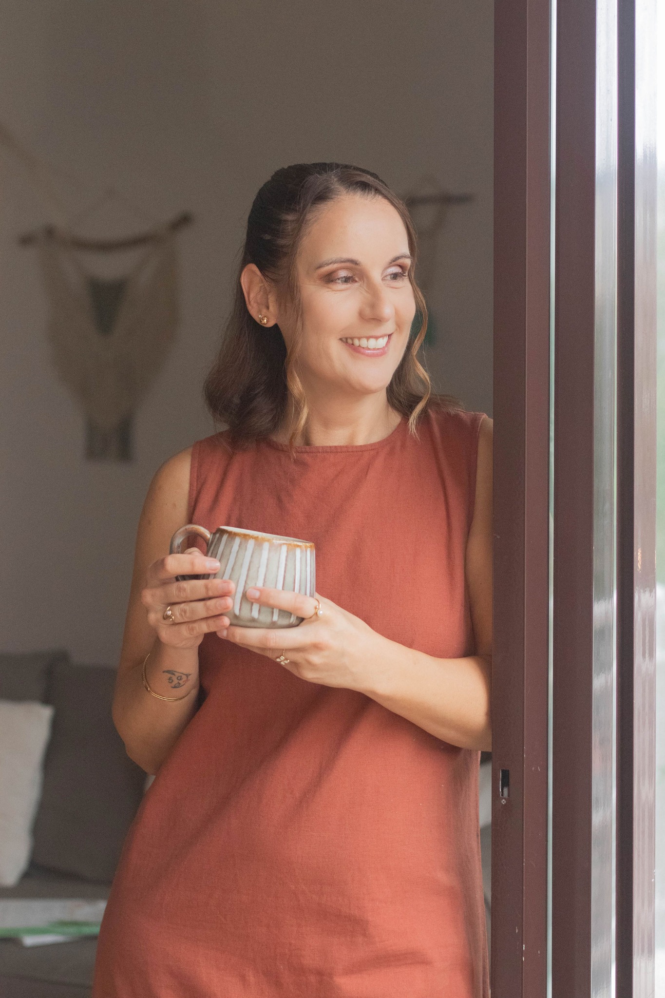 Paula Neto em casa, junto à janela, com uma chávena
